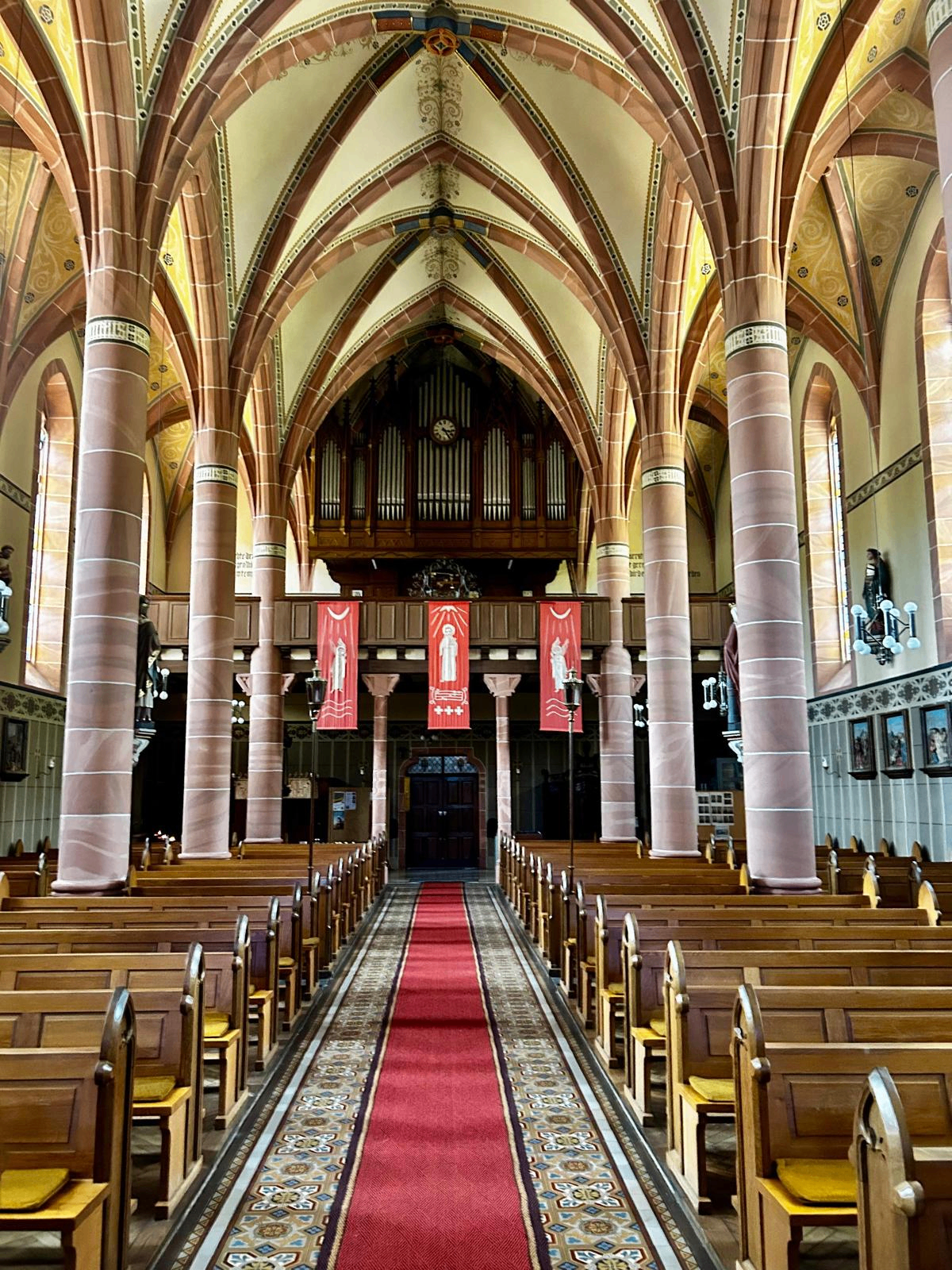 Blick durchs Kirchenschiff zur Orgelempore mit roten Bannern